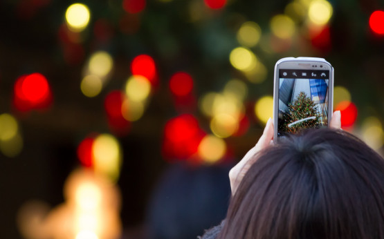 Jemand macht mit dem Smartphone ein Foto von einem Weihnachtsbaum
